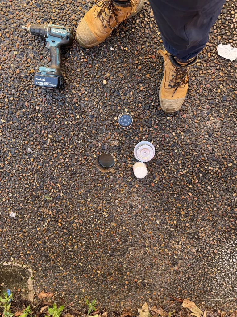 Drilled access opening in a concrete or paved surface beside treatment equipment