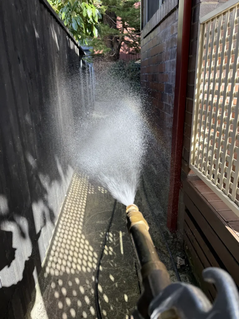 Outdoor pest treatment spray along a narrow side passage