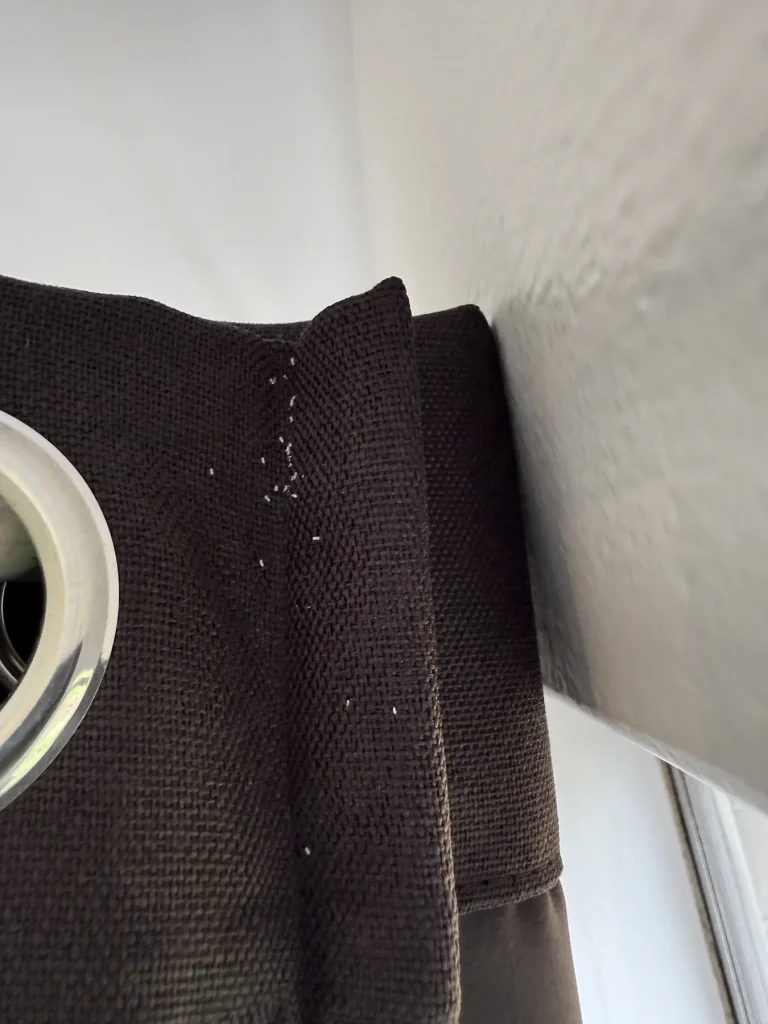 Pale wall and dark fabric upholstery seam viewed during inspection