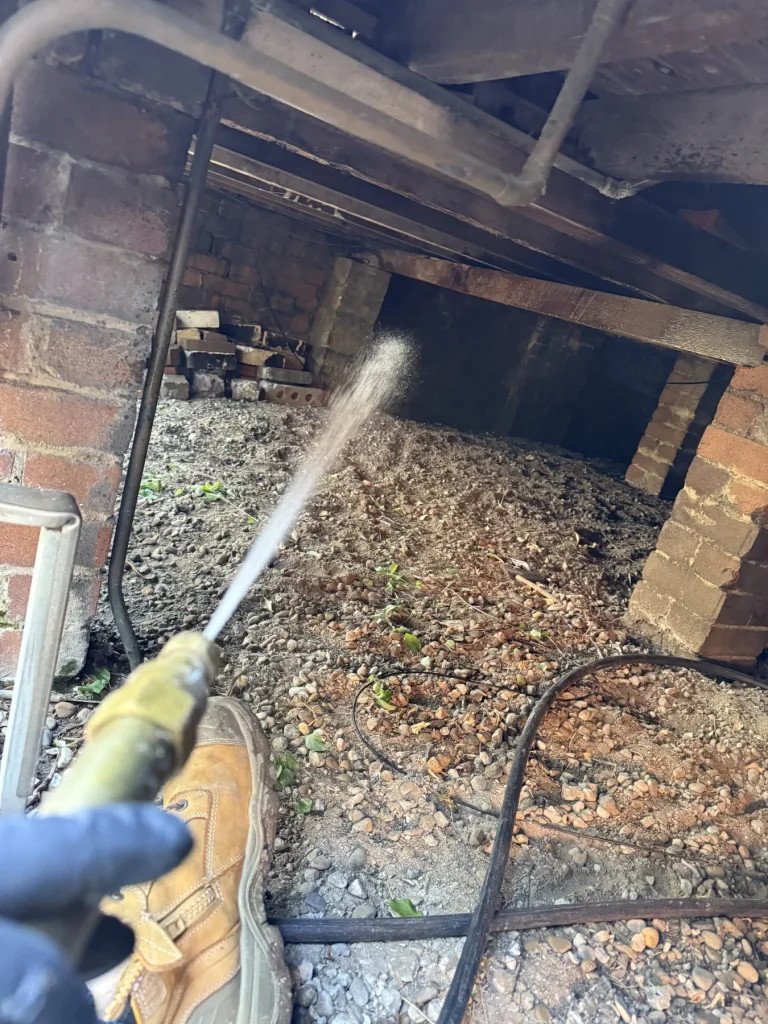 Treatment application beside brick foundations in a subfloor