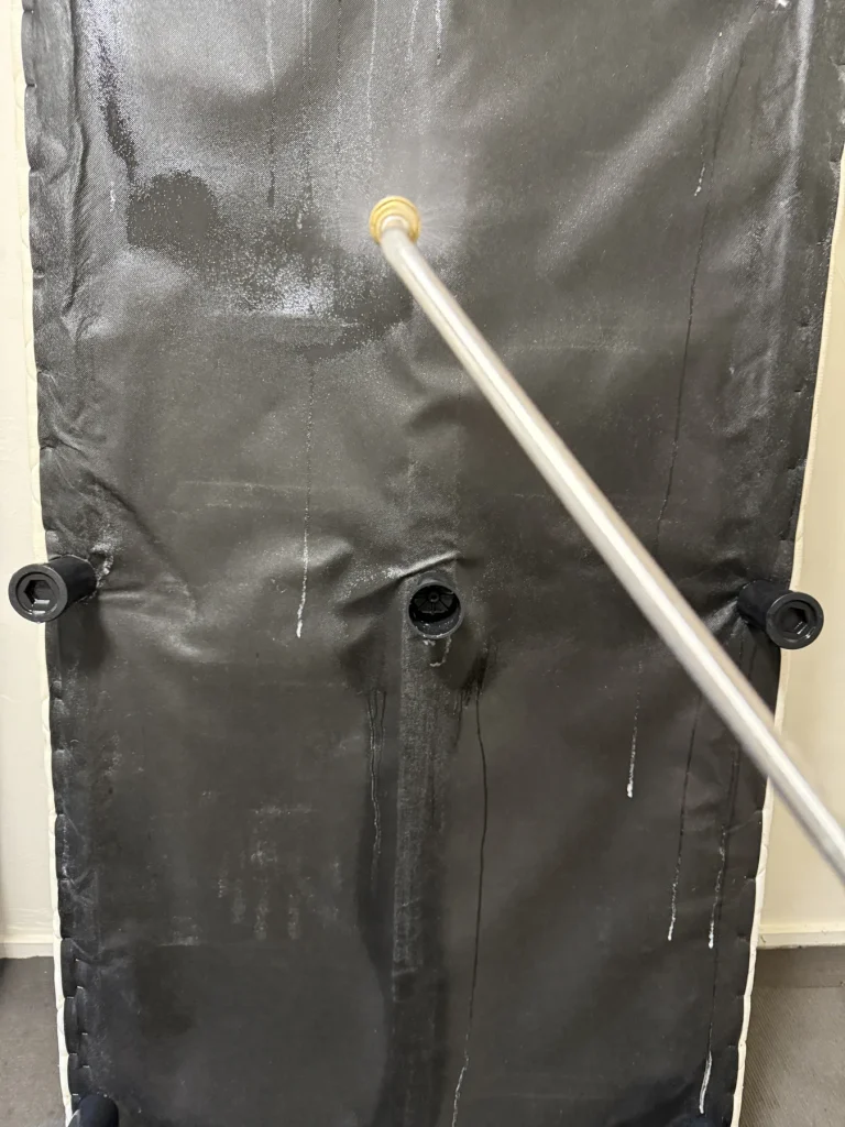 Inspection probe pointing at punctures in dark upholstered fabric