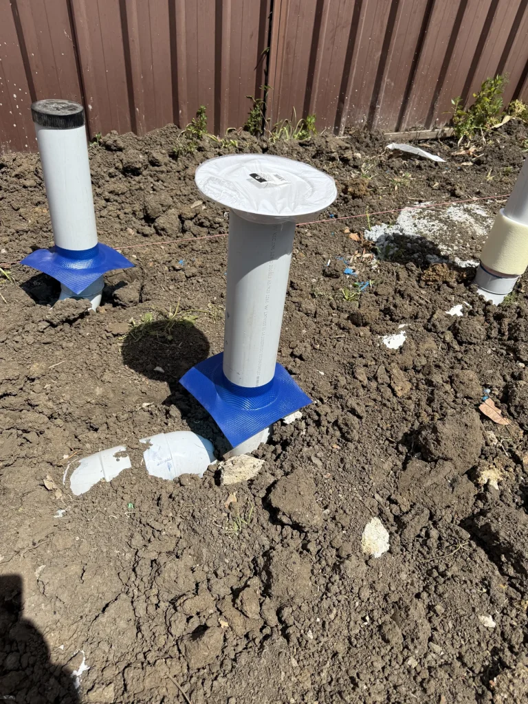 White termite treatment or monitoring devices set in exterior soil