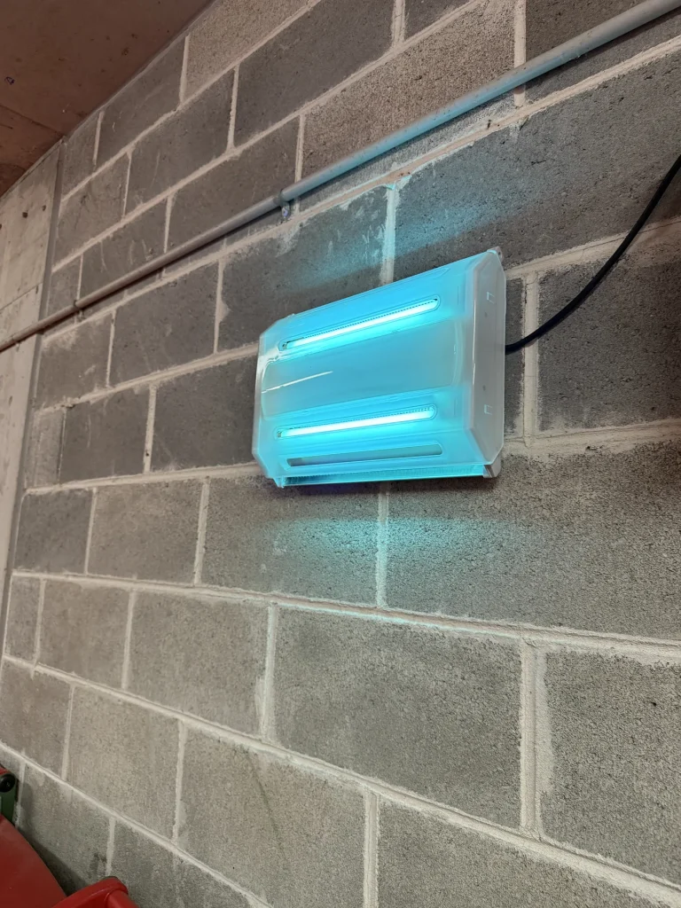 Blue wall-mounted ventilation fan or unit installed on exterior brickwork