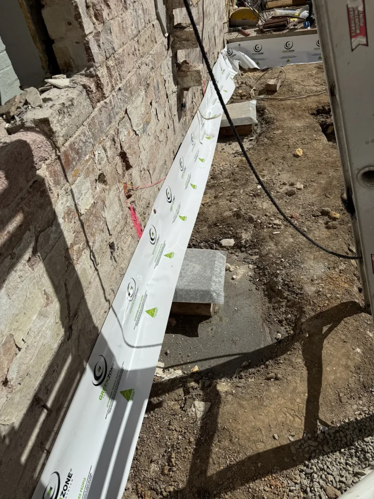 White protection strip fixed along the edge of a brick wall foundation