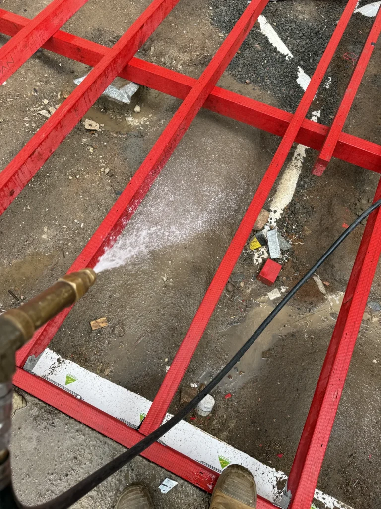Red metal floor framing and treatment nozzle at a construction site