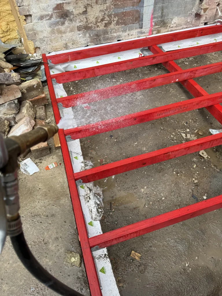 Red metal floor framing inside a partially stripped room