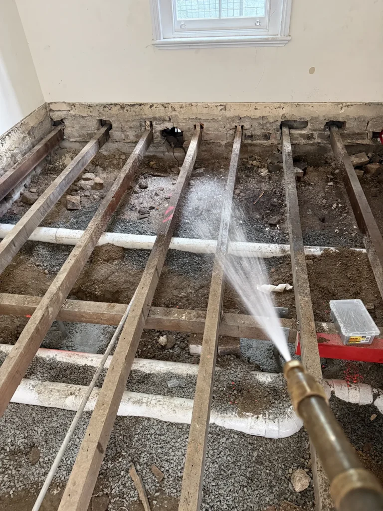 Treatment nozzle directed across exposed floor joists and void