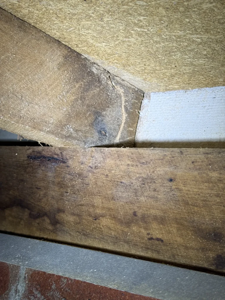 Cracked surface and discoloured junction near a timber roof member