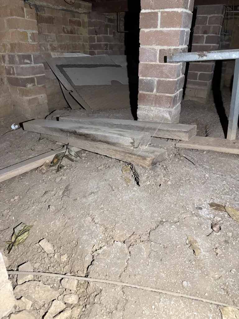 Exposed brick foundation pier and dusty ground in a crawlspace