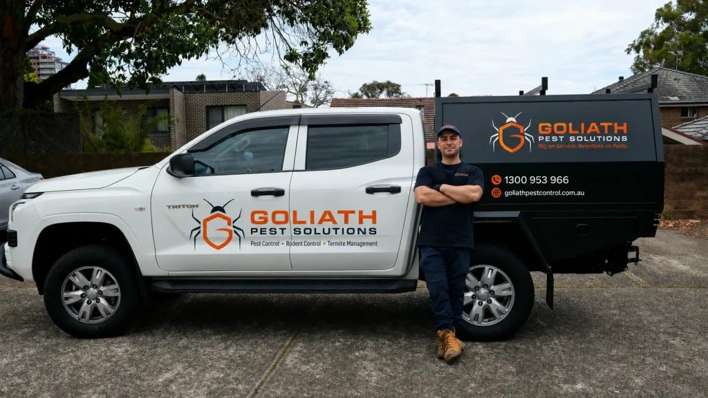 Goliath pest control technician standing beside the branded ute