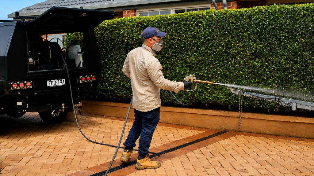 Goliath technician applying a treatment along an outdoor paved area