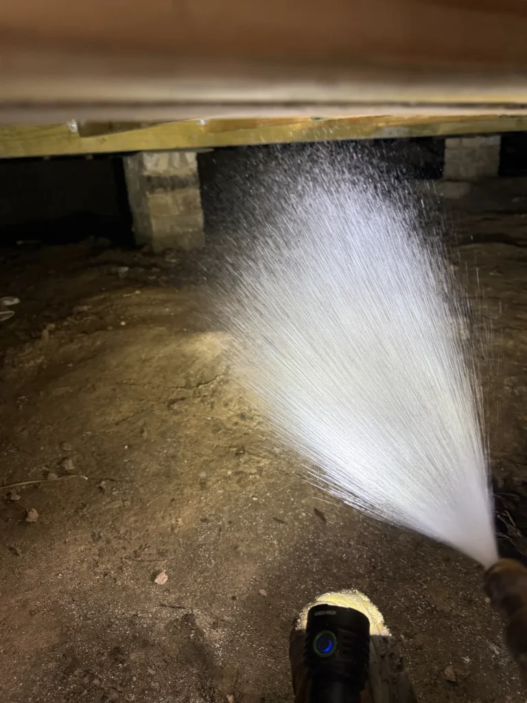 Pest-control treatment being applied within a residential subfloor