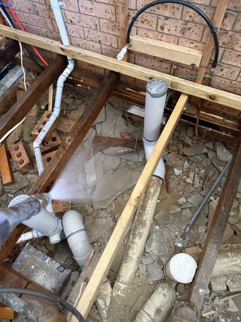 Pest treatment application across exposed plumbing and floor joists